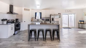 Une cuisine moderne dotée d’un îlot central, de tabourets de bar et d’une enseigne de style rustique.