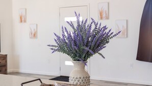 Une pièce dans laquelle se trouve un plateau en bois portant un vase de lavande et une boîte de thé Swiss Miss.
