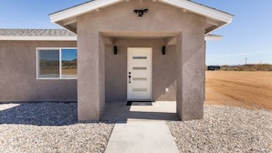 Un bâtiment d’un seul étage, doté d’un toit plat, d’une entrée centrale avec une porte et d’une petite fenêtre sur le côté gauche.