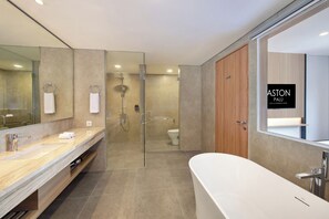 Un baño moderno con una bañera grande, una ducha con mampara de vidrio y un inodoro.