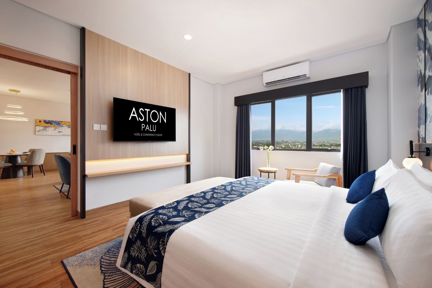 Une chambre d’hôtel moderne avec un grand lit, un téléviseur fixé au mur, un bureau et une vue sur la ville.