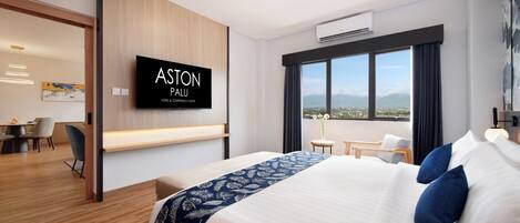 A modern hotel room with a large bed, a TV on the wall, a desk, and a view of the city.