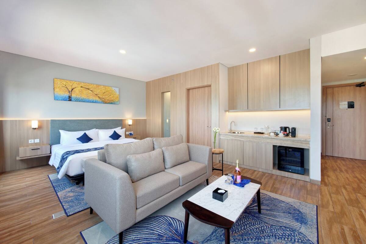 Une chambre d’hôtel moderne équipée d’un lit, d’un canapé, d’une table basse et d’une kitchenette.