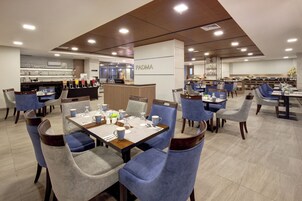 Un comedor moderno con varias mesas y sillas, un mostrador de recepción y una zona de cocina al fondo.