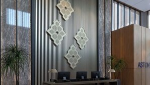 A reception desk with a modern design, flanked by vertical slats and hexagonal patterns, and a wooden panel with the word "ASTON" on it. - Aston Palu Hotel & Conference Center (Palu)