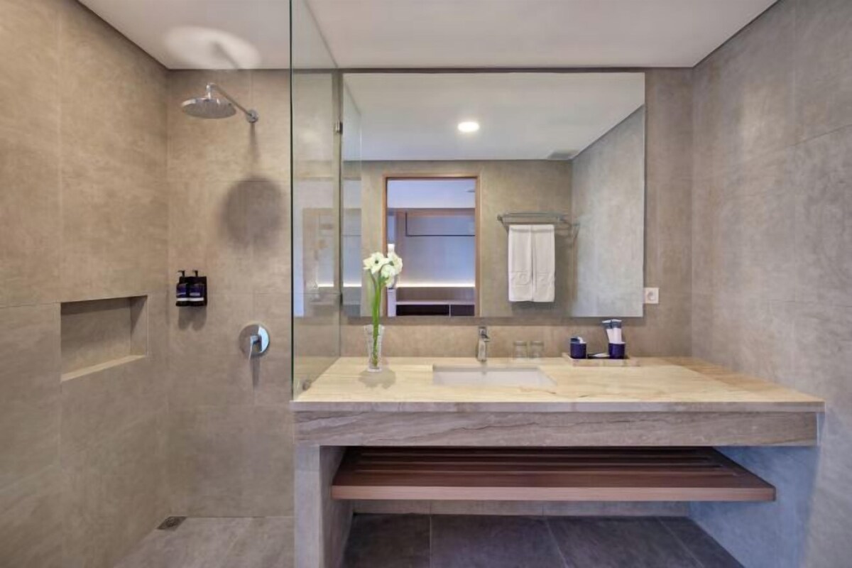 A modern bathroom with a glass-enclosed shower, a sink with a marble countertop, and a large mirror reflecting the room.