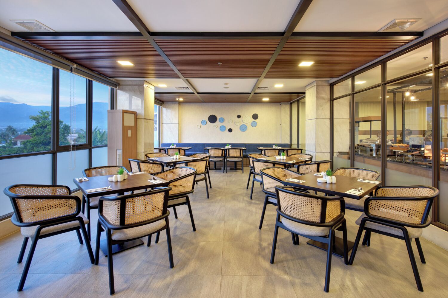 A conference room with round tables and chairs, large windows, and a view of the outdoors.