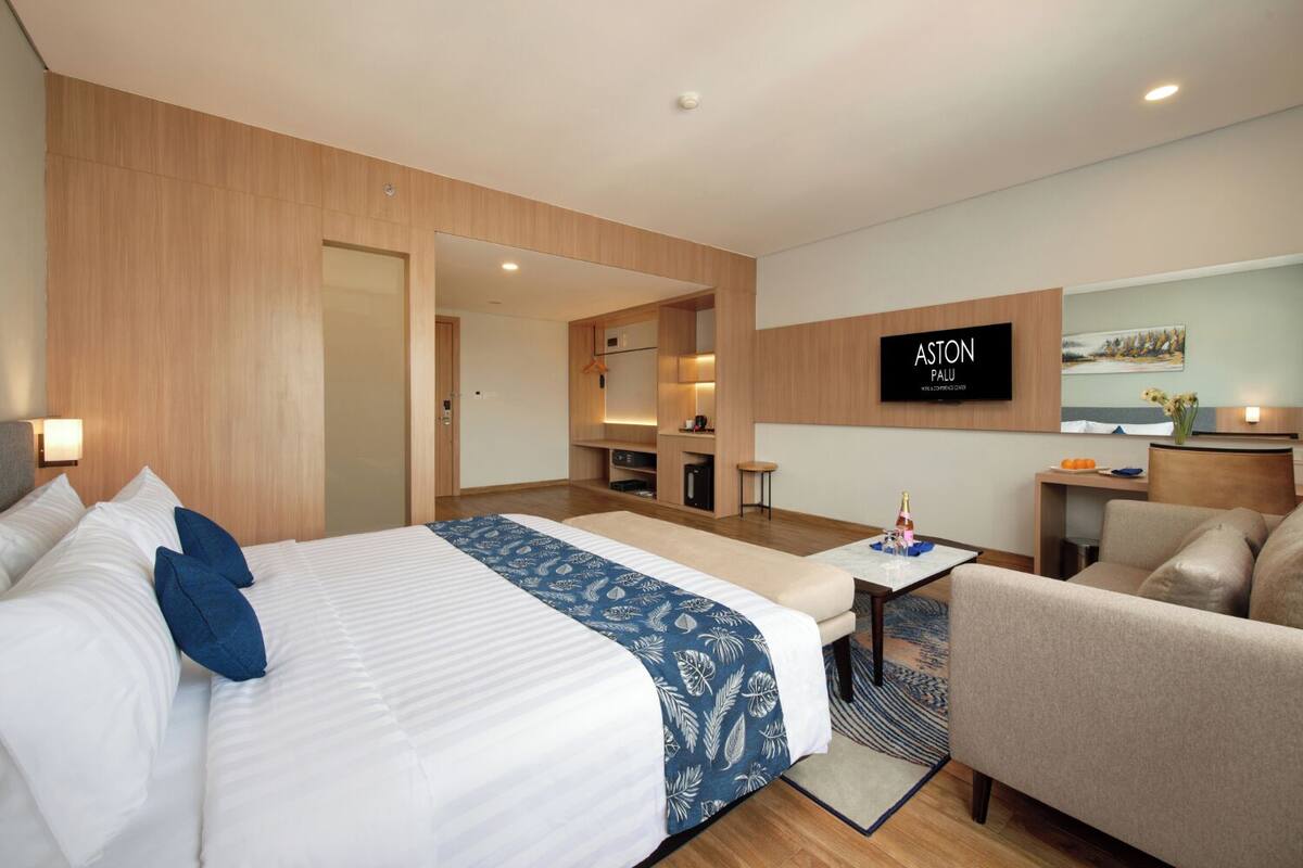 Une chambre d’hôtel comprenant un lit, un canapé, une petite table, une télévision et une kitchenette.