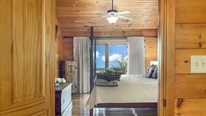 A wooden interior with a bed, a ceiling fan, and a window with a view. - Amazing Overlook Mtn Cabin Near DT Blue Ridge (Blue Ridge)