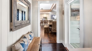 Un couloir avec un banc en bois, un miroir et un coin repas comprenant des chaises et une table.