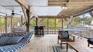 Une terrasse extérieure couverte, dotée d’un plancher en bois, d’un hamac, d’un canapé et d’une table.