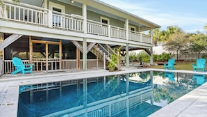 Une maison à deux étages avec une piscine, un espace salon extérieur et un patio couvert.