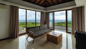 A spacious living room with a large sofa, a wooden coffee table, and a view of the ocean through expansive windows. - Vivo P Villa by Betterplace (Kutuh)
