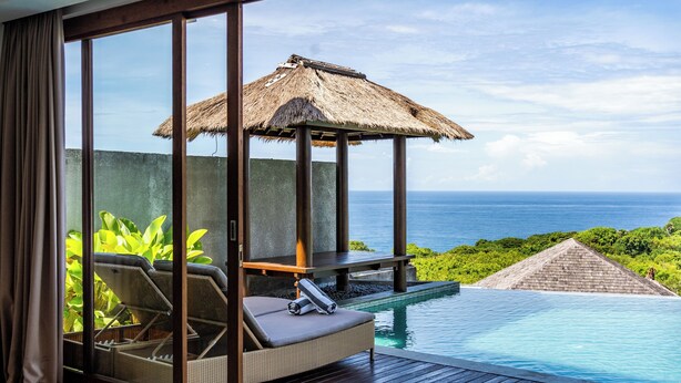 A private pool area with a lounge chair and a thatched umbrella, overlooking a lush landscape and the sea. - Vivo P Villa by Betterplace (Kutuh)