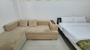 A room with a beige sofa, a white bed, and a patterned wall. - Green Apartment Kaset (Bangkok)