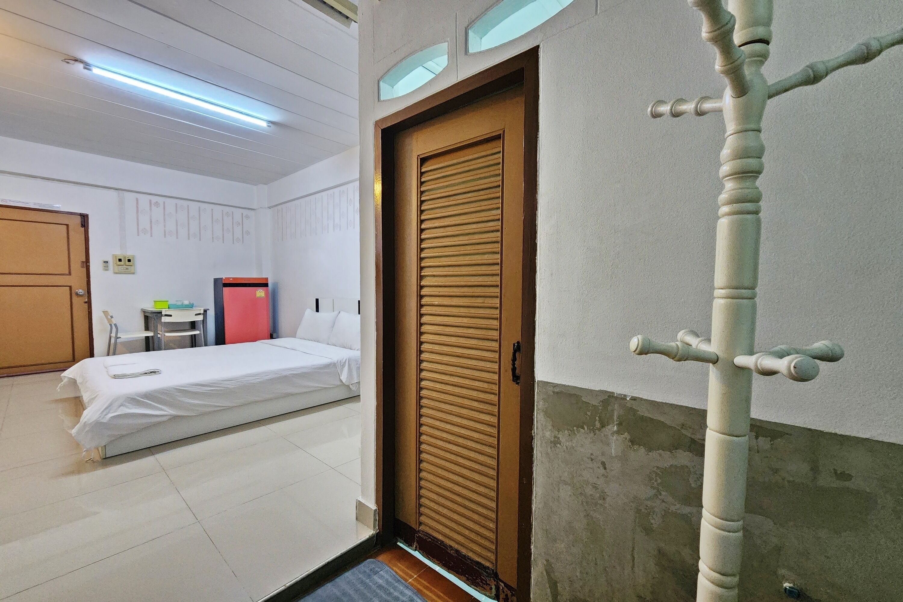 Una habitación de hotel con una cama, una puerta, una mesita y una silla.