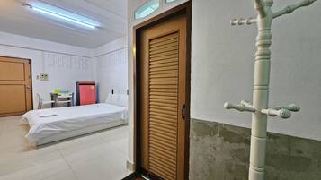 Una habitación de hotel con una cama, una puerta, una mesita y una silla.