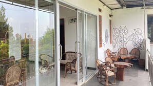 A balcony with glass doors, wicker furniture, and a wall with leaf patterns.