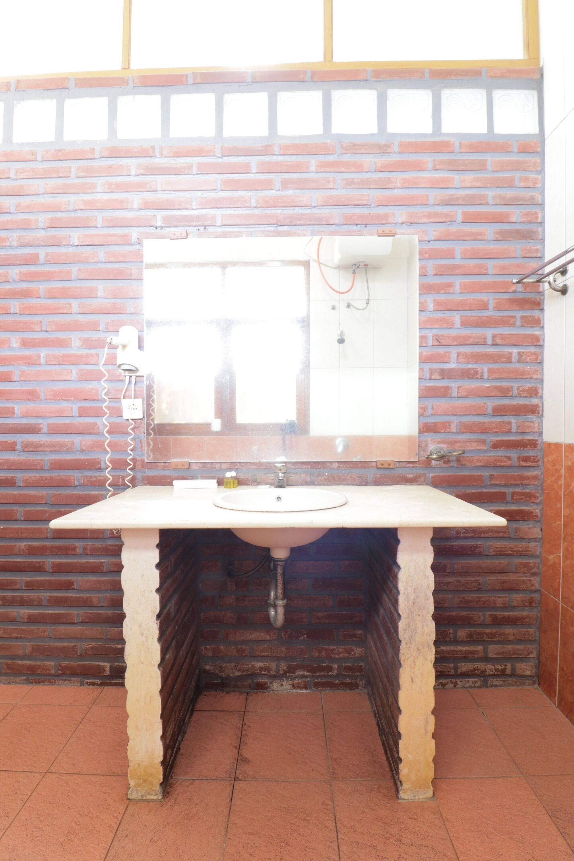 A bathroom with a white sink, a mirror, and a brick wall.