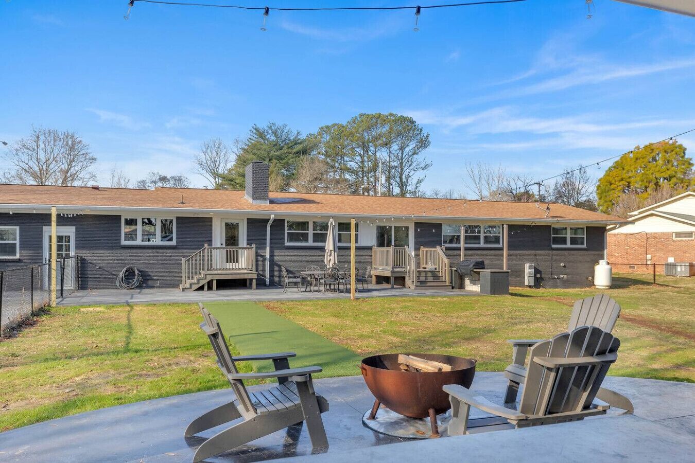A two-story building with a covered patio area, outdoor seating, and a fire pit.