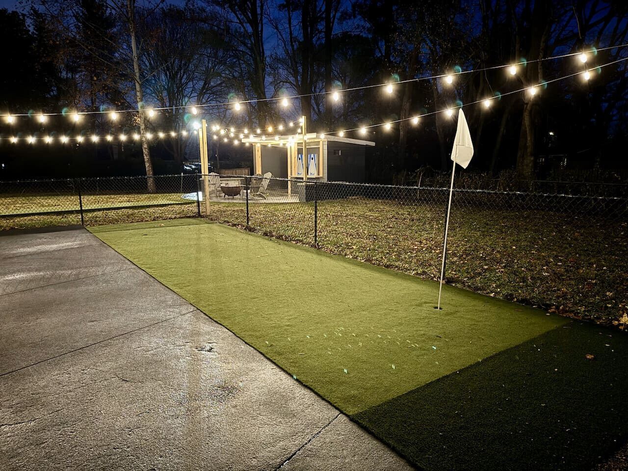 A well-lit outdoor area with artificial lighting, a small structure, and a flag.