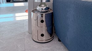 Une chambre à coucher moderne avec un lit, une lampe métallique et un téléviseur en arrière-plan.