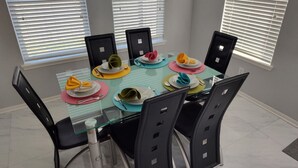 A dining table with four chairs, set with plates, cutlery, and napkins.