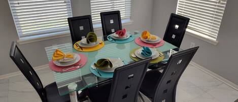 Una mesa de comedor con cuatro sillas, puesta con platos, cubiertos y servilletas.