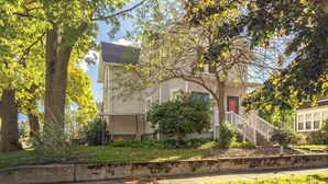 A two-story house with a front porch, a small tree, and a red door. - The Lighthouse: Large home close to downtown with a hot tub & game room! (South Haven)