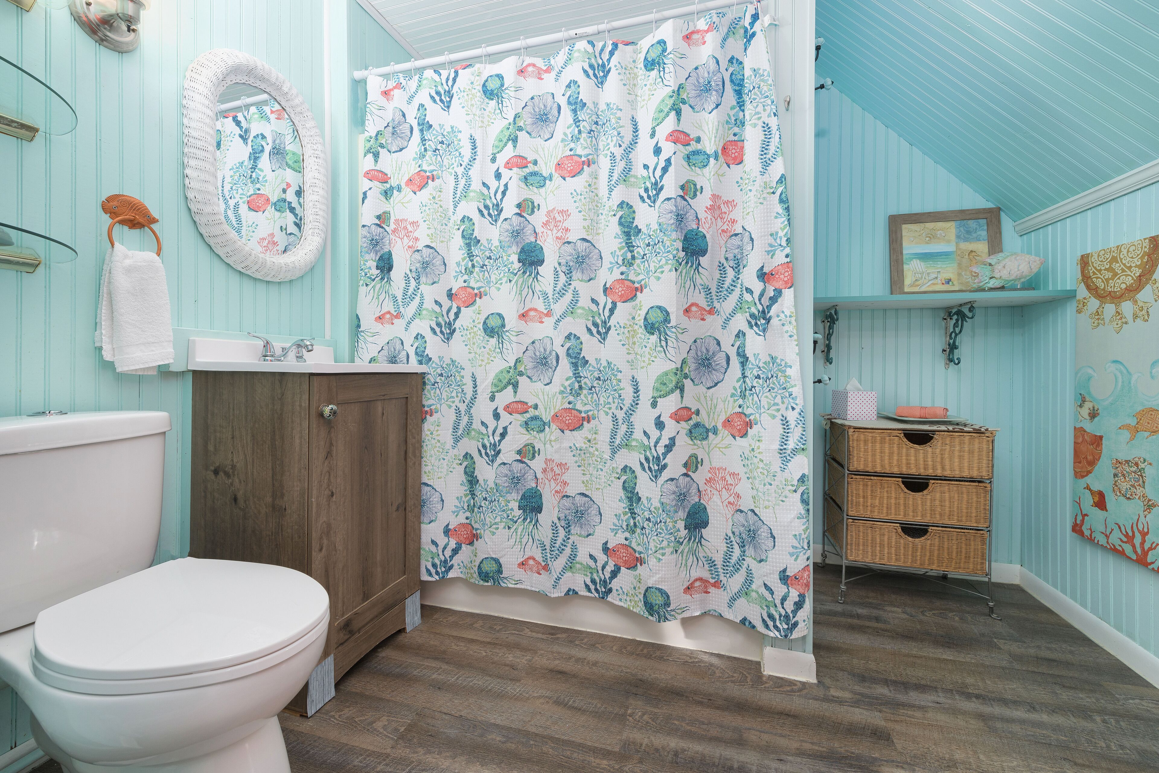 Un baño con inodoro, armario de madera y cortina de ducha estampada con motivos florales.
