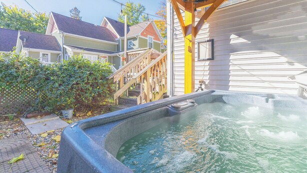 A hot tub area with a wooden deck and stairs leading to a house. - The Lighthouse: Large home close to downtown with a hot tub & game room! (South Haven)