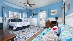 A bedroom with a bed, a desk, a chair, a sofa, and a ceiling fan. - The Lighthouse: Large home close to downtown with a hot tub & game room! (South Haven)