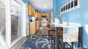 A kitchen with wooden cabinets, a dining table, and a blue wall with a calendar. - The Lighthouse: Large home close to downtown with a hot tub & game room! (South Haven)