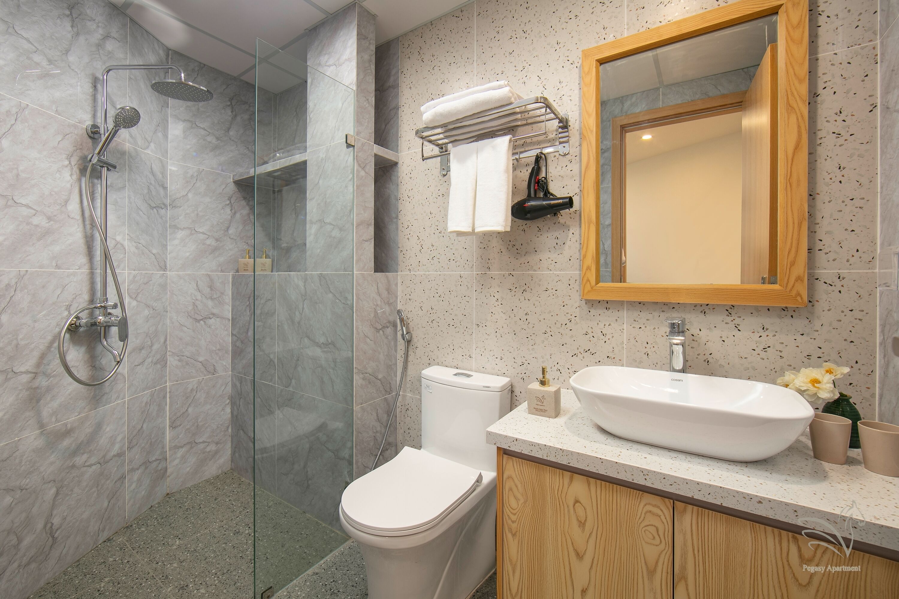 Ein modernes Badezimmer mit einer Duschkabine aus Glas, einer weißen Toilette, einem hölzernen Waschtisch mit Waschbecken und einem Spiegel darüber.