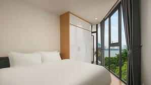 Una camera da letto moderna con un letto grande, un armadio in legno e vista sulla città attraverso ampie finestre.