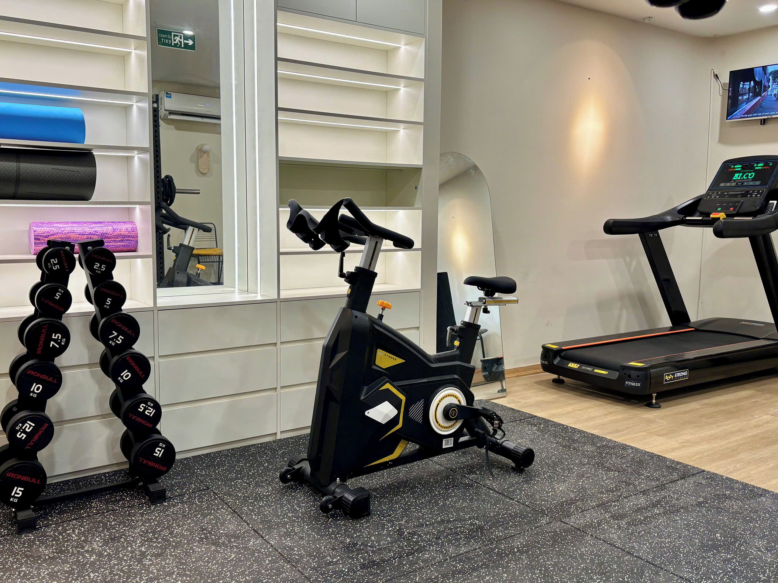 A gym with exercise equipment, a treadmill, and a mirrored wall.