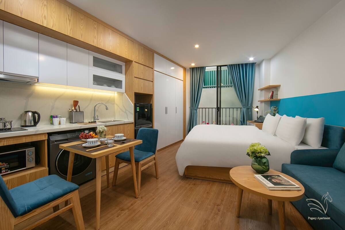 Une chambre d’hôtel compacte comprenant un coin cuisine, un lit, un canapé et un petit espace repas.