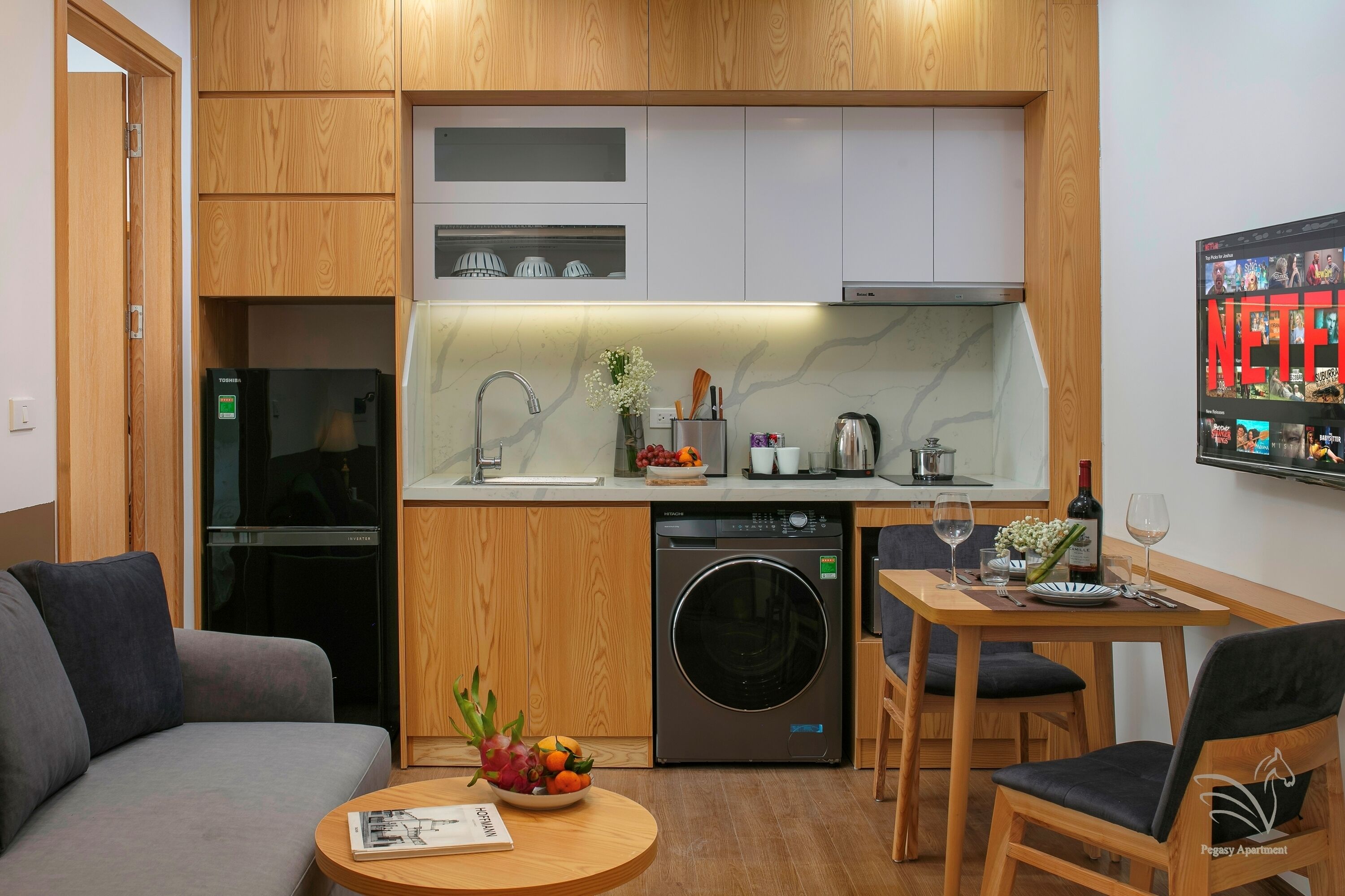 A compact living space with a kitchenette, a washing machine, a dining area, and a sofa.