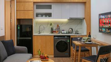 A compact living space with a kitchenette, a washing machine, a dining area, and a sofa.