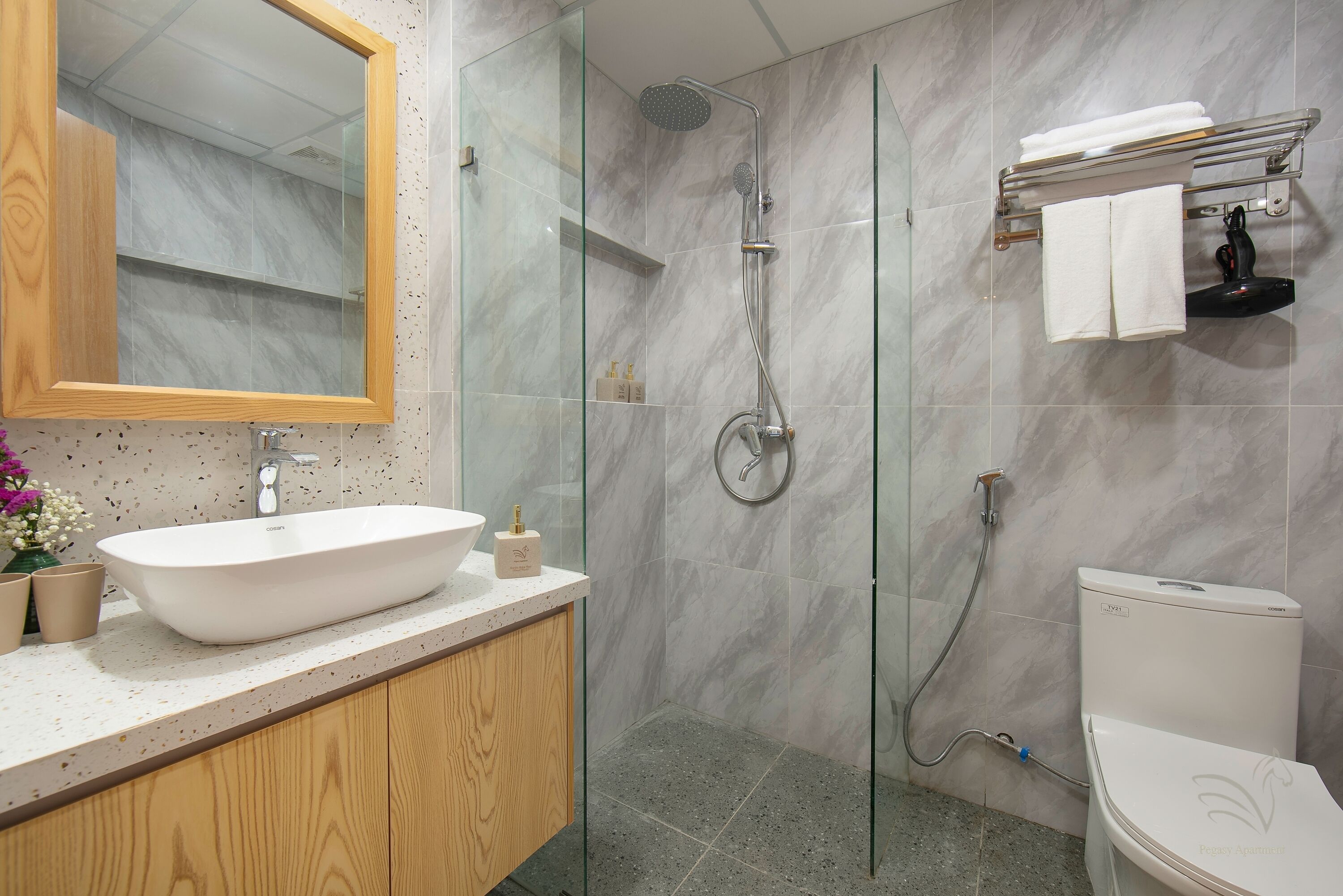Un baño moderno con ducha de vidrio, lavamanos blanco y retrete.