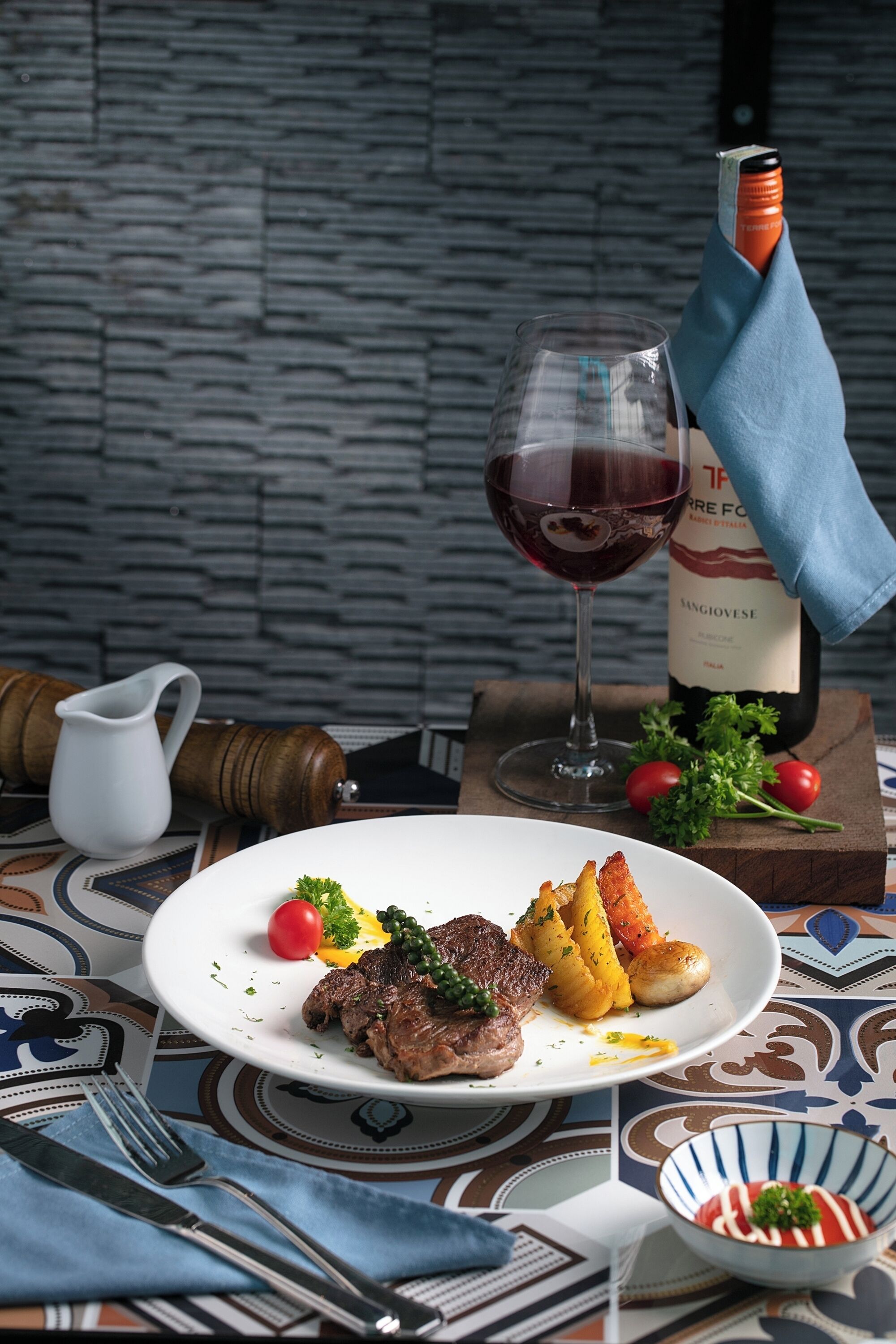A dining table with a plate of food, a wine glass, and a bottle of wine.