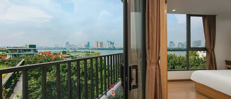 A modern bedroom with a large window, a balcony with flowers, and a city view.