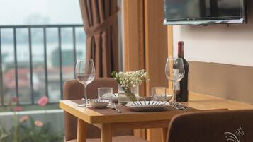 A dining table set with plates, glasses, and cutlery, a bottle of wine, and a vase with flowers.