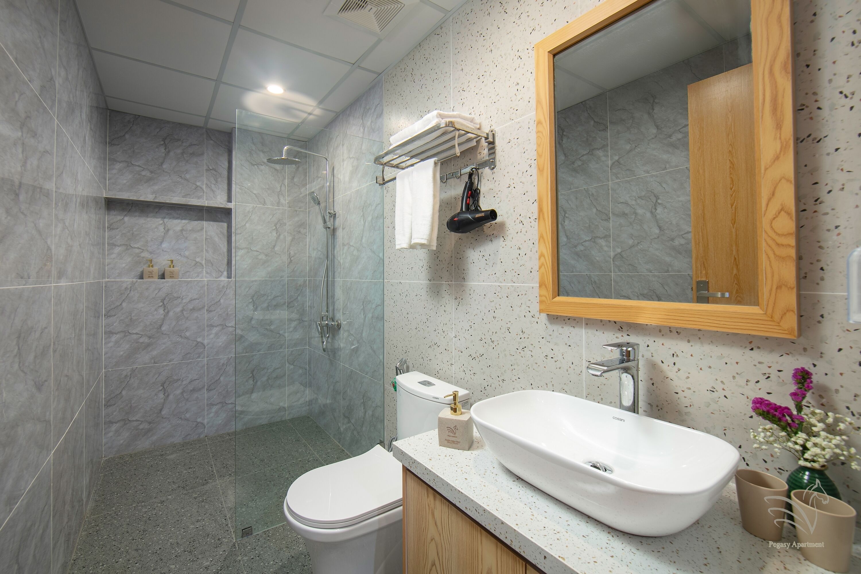 Une salle de bain moderne avec une douche à parois de verre, un lavabo blanc et un meuble-lavabo en bois.