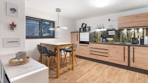 Une cuisine moderne avec des meubles en bois, un coin repas comprenant une table et des chaises, et une grande fenêtre.