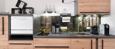 A modern kitchen with a built-in dishwasher, a coffee machine, and a sink.