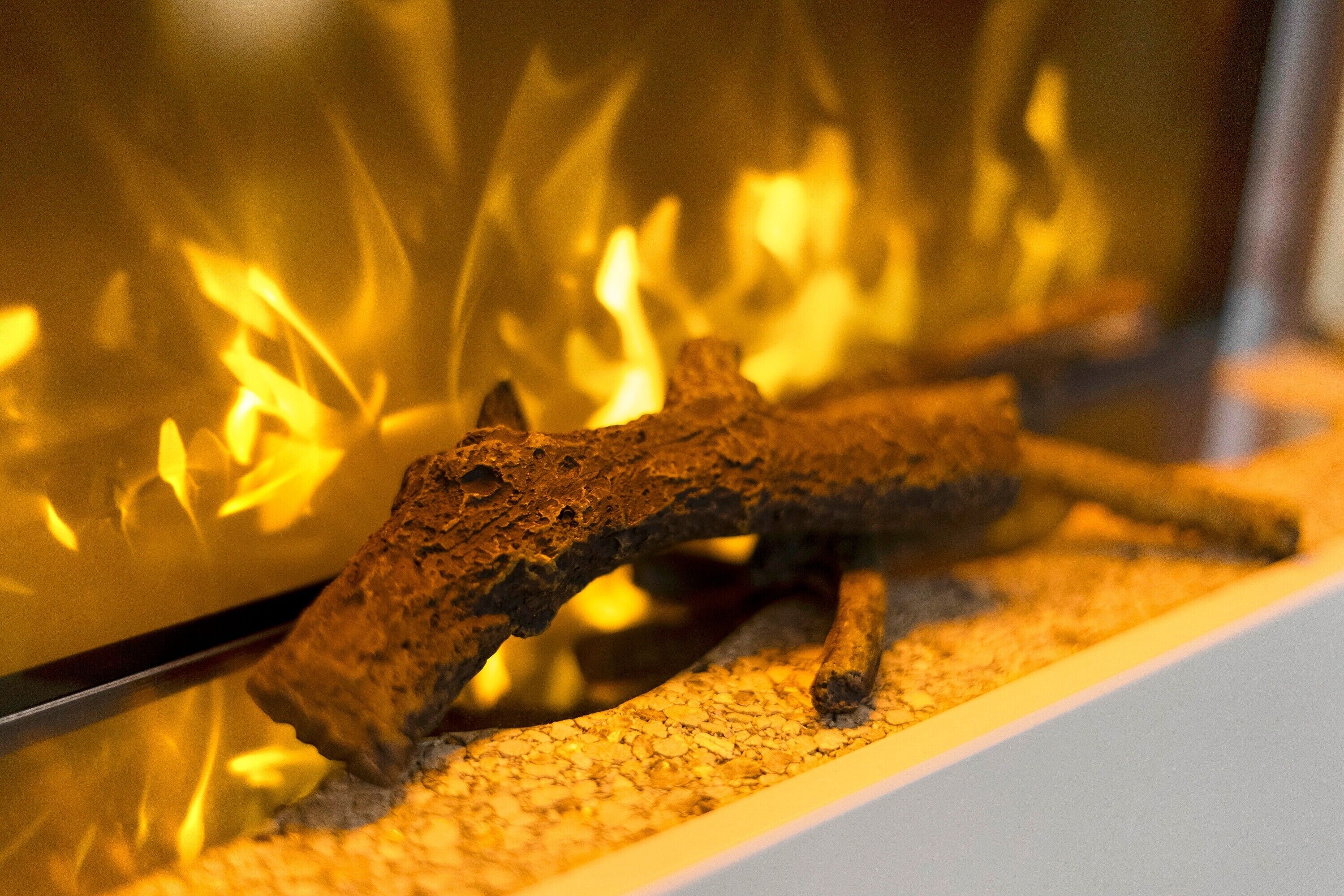 A fireplace with a log, a glass enclosure, and a fire burning inside.