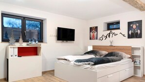Une chambre à coucher avec un lit, un bureau avec une télévision et des œuvres d’art accrochées aux murs.