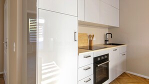 Una cocina compacta con armarios blancos, un horno negro y una encimera de madera.