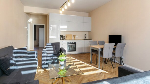 Una sala de estar moderna con una mesa de centro de vidrio, un sofá y un comedor con sillas.